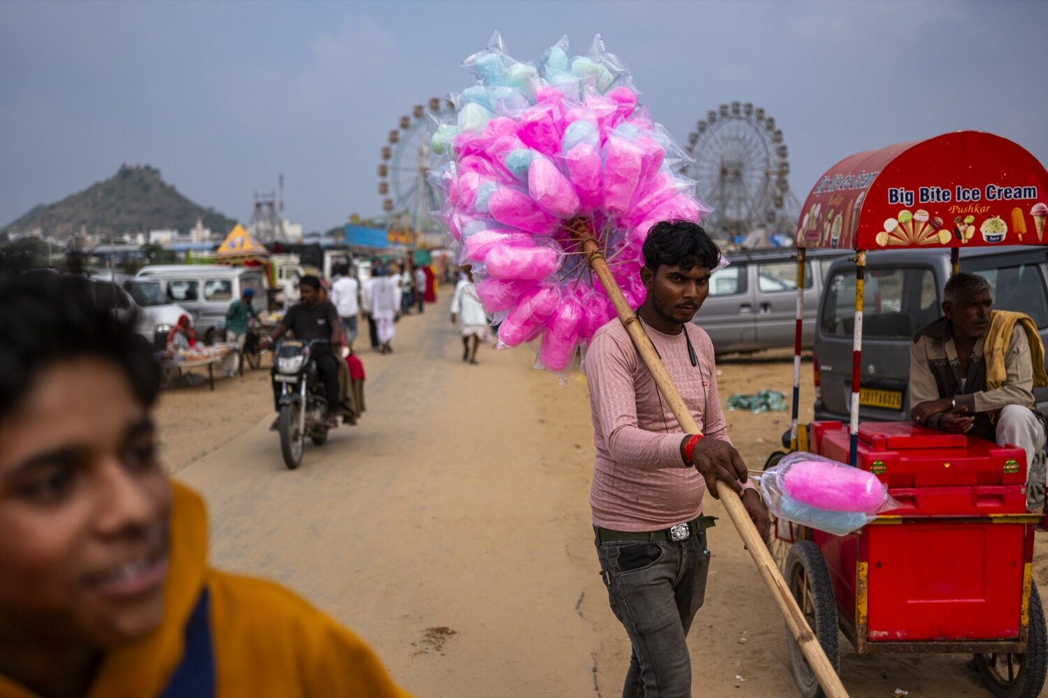 Vendedor de algodão doce na feira Pushkar Camel Fair com roda gigante ao fundo, Rajastão