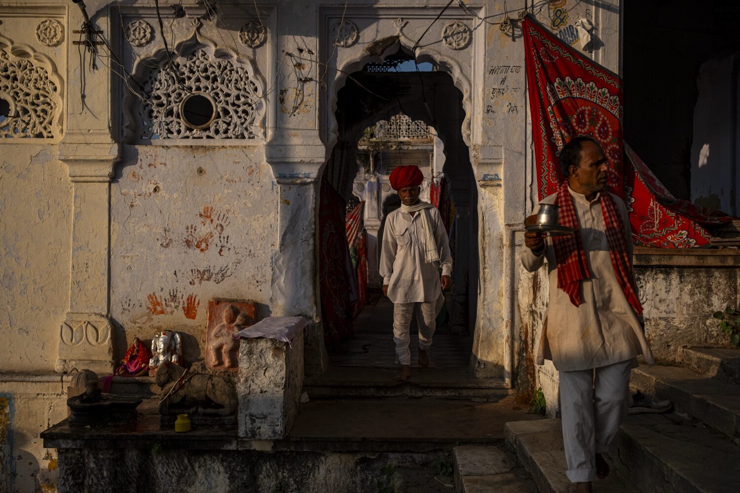 Homens em vestes brancas e turbante vermelho num templo em Pushkar, Rajastão