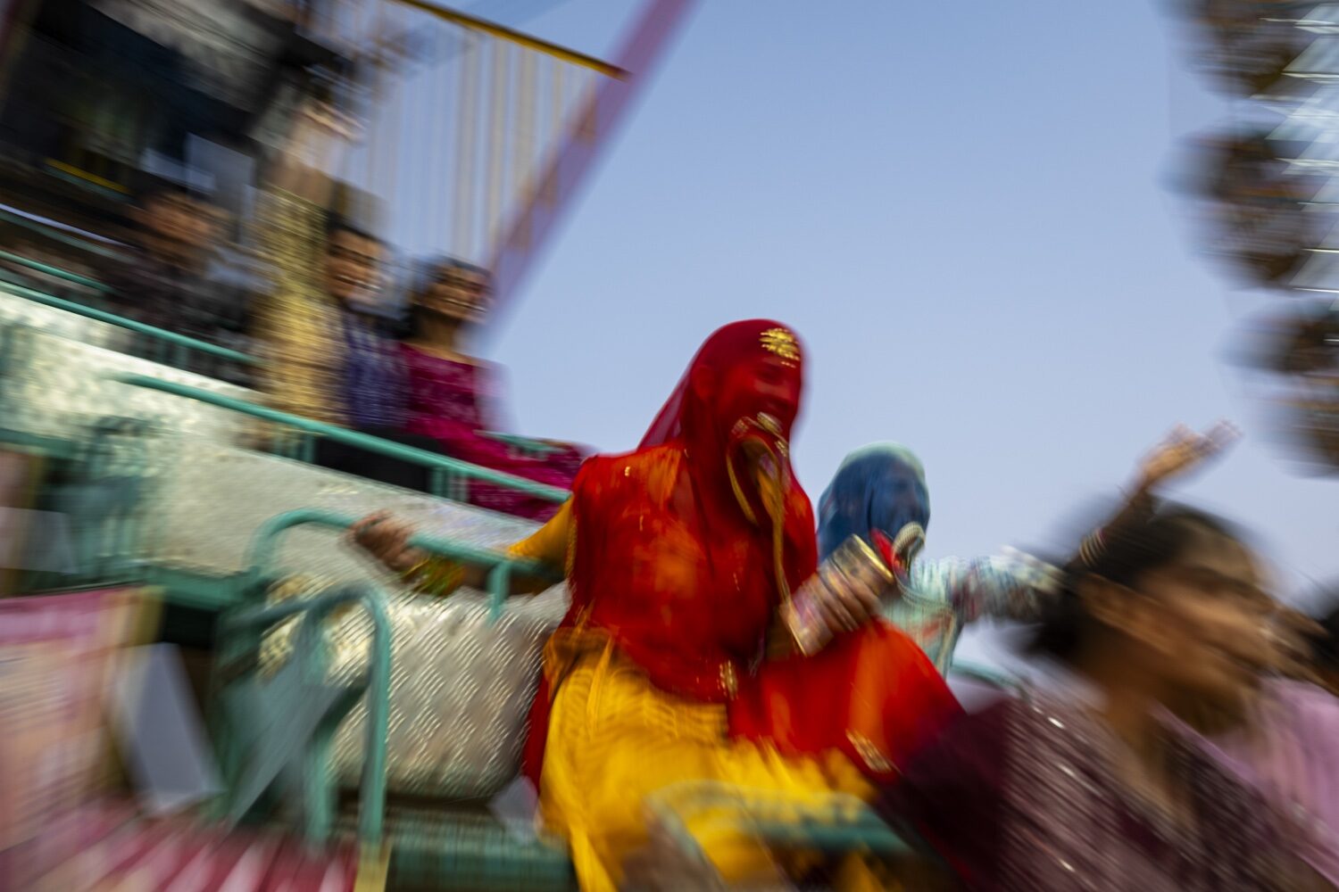Mulheres em saris vermelhos e amarelos num divertimento da feira de Pushkar