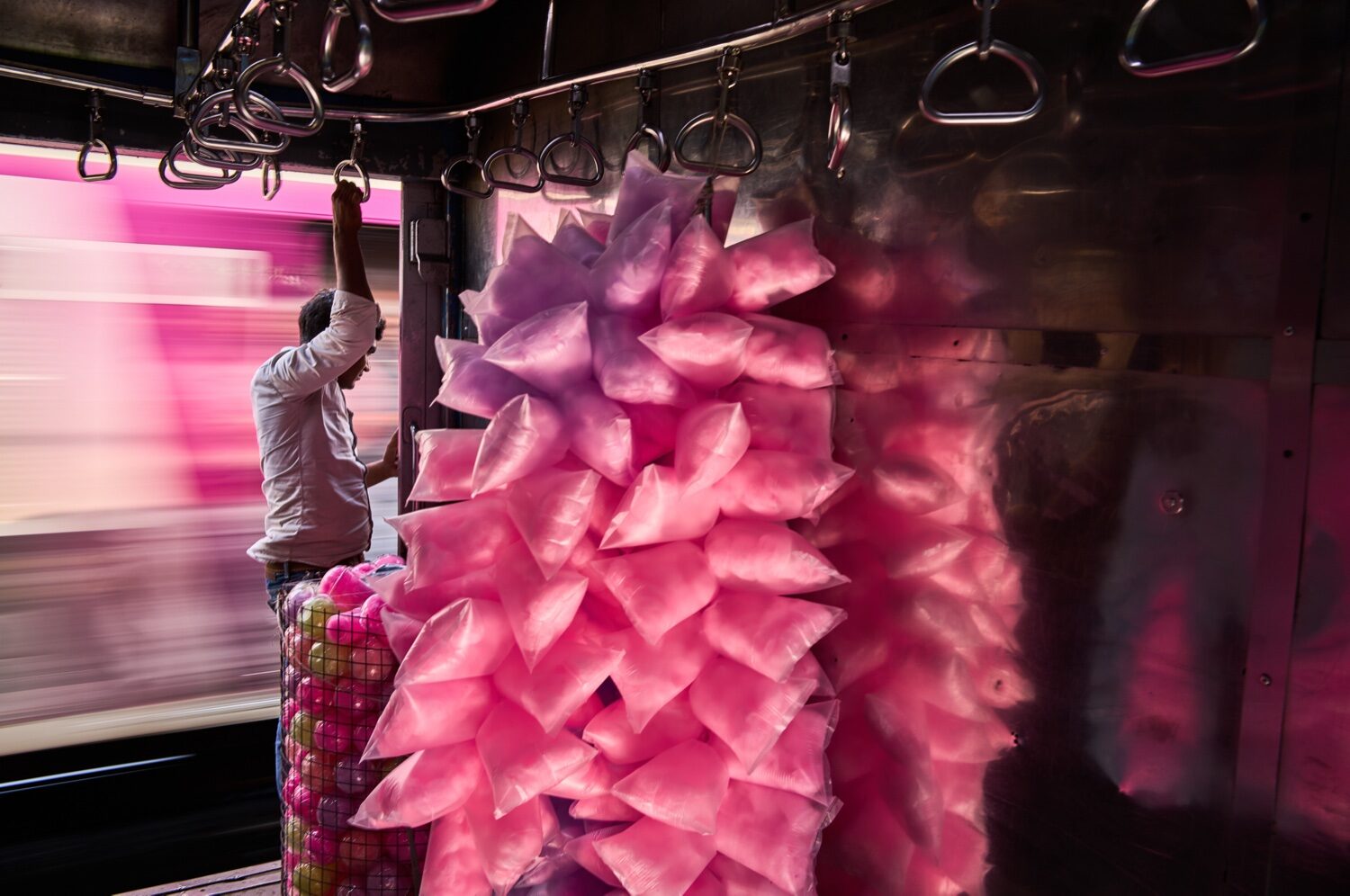 Vendedor de algodão doce cor-de-rosa numa carruagem do Mumbai Local em movimento