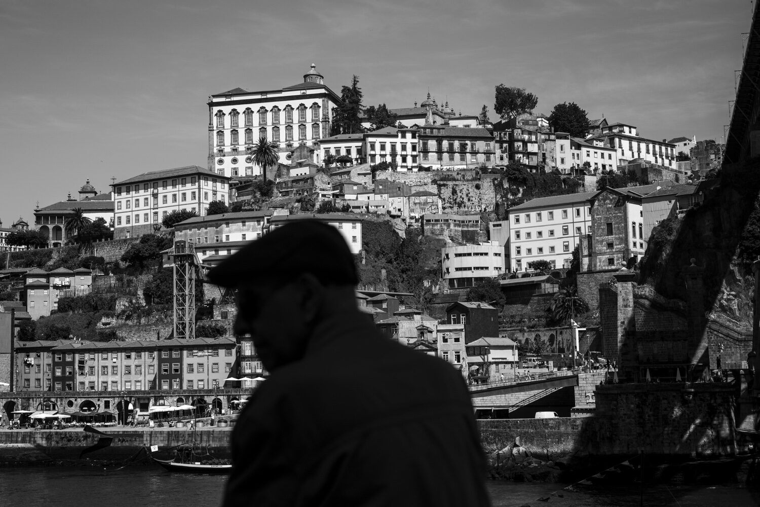 Homem com boina em primeiro plano com Paço Episcopal e Ribeira do Porto a preto e branco