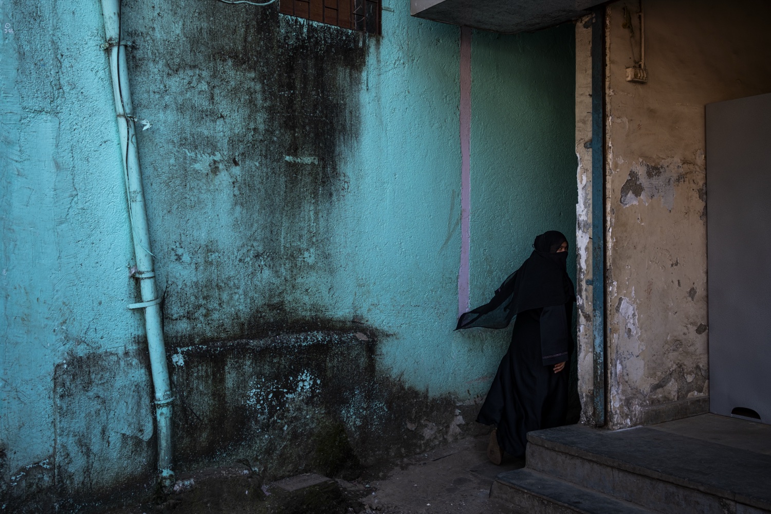 Woman in black against a turquoise wall, Mumbai