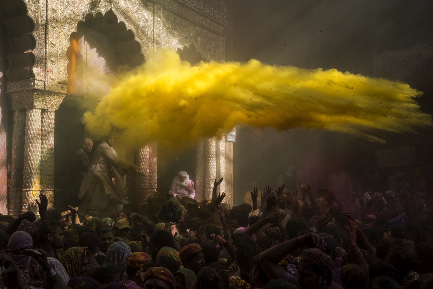 Yellow colour cloud in the air inside a Vrindavan temple during Holi